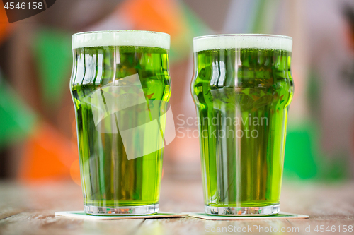 Image of two glasses of green beer on wooden table