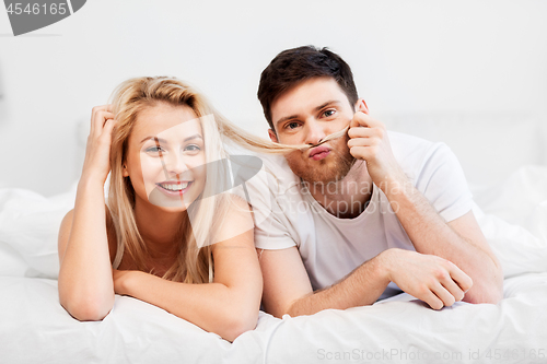 Image of happy couple lying in bed at home