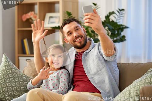 Image of father and daughter taking selfie at home