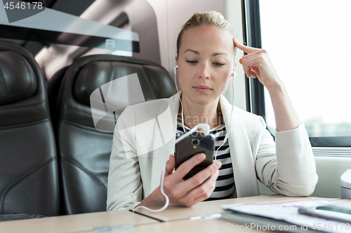 Image of Businesswoman communicating on mobile phone while traveling by train.