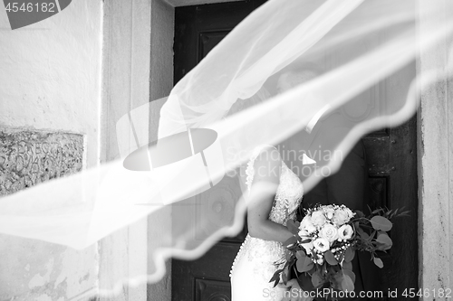 Image of The kiss. Bride and groom kisses tenderly in the shadow of a flying veil. Artistic black and white wedding photo.