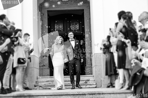 Image of Newlyweds exiting the church after the wedding ceremony, family and friends celebrating their love with the shower of soap bubbles, custom undermining traditional rice bath