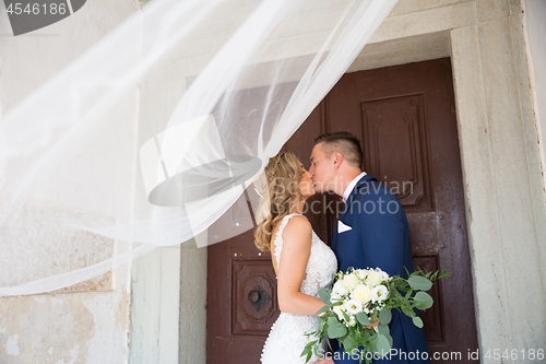 Image of The kiss. Bride and groom kisses tenderly in the shadow of a flying veil. Artistic black and white wedding photo.