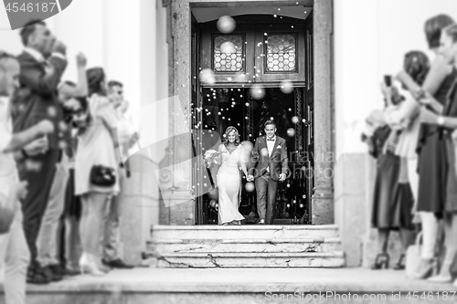 Image of Newlyweds exiting the church after the wedding ceremony, family and friends celebrating their love with the shower of soap bubbles, custom undermining traditional rice bath