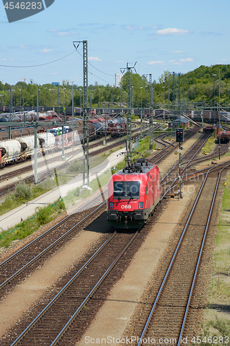 Image of Red locomotive moving through railroad cargo marshalling station