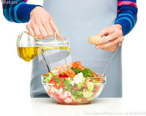 Image of Cook is pouring olive oil into salad