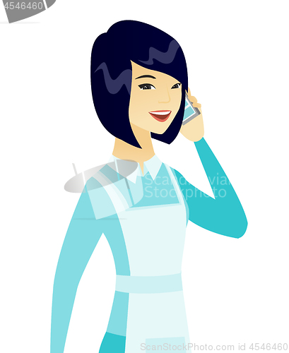 Image of Young asian cleaner talking on a mobile phone.