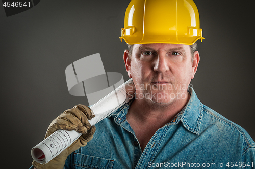 Image of Serious Contractor in Hard Hat Holding Floor Plans With Dramatic