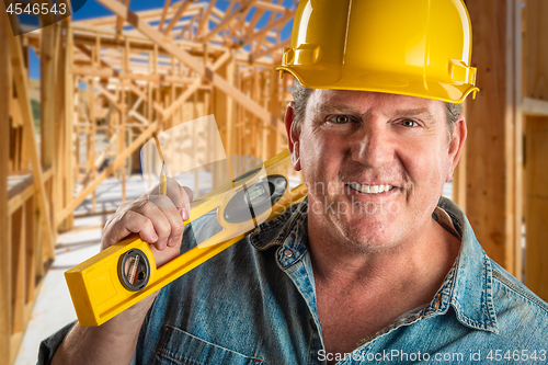 Image of Smiling Contractor in Hard Hat Holding Level and Pencil At Const