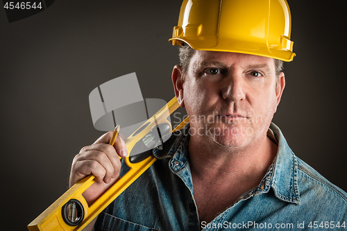 Image of Serious Contractor in Hard Hat Holding Level and Pencil With Dra