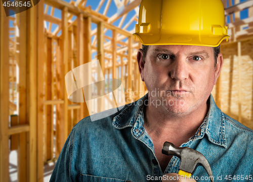 Image of Serious Contractor in Hard Hat Holding Hammer At Construction Si