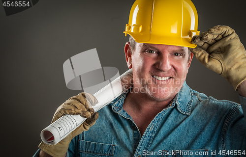 Image of Smiling Contractor in Hard Hat Holding Floor Plans With Dramatic