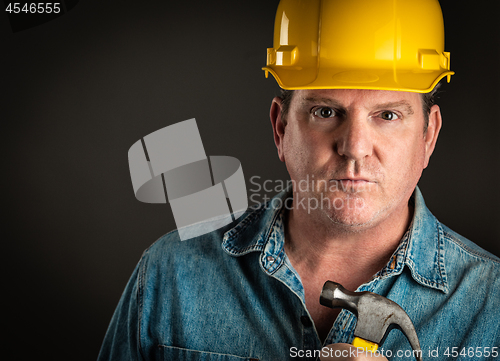 Image of Serious Contractor in Hard Hat Holding Hammer With Dramatic Ligh