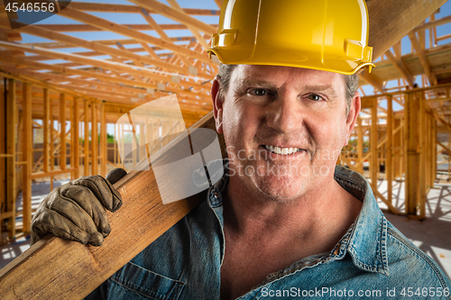 Image of Smiling Contractor in Hard Hat Holding Plank of Wood At Construc