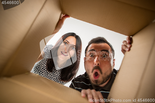 Image of The couple unpacking and opening carton box and looking inside