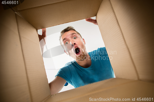 Image of Man smiling, unpacking and opening carton box and looking inside