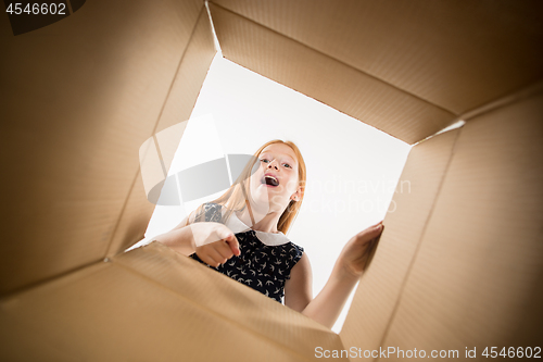 Image of The girl unpacking and opening carton box and looking inside