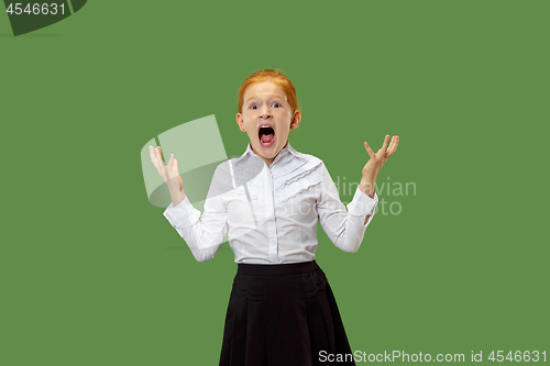 Image of The young emotional angry teen girl screaming on green studio background