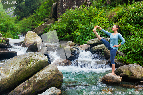 Image of Woman doing Ashtanga Vinyasa Yoga asana outdoors at waterfall