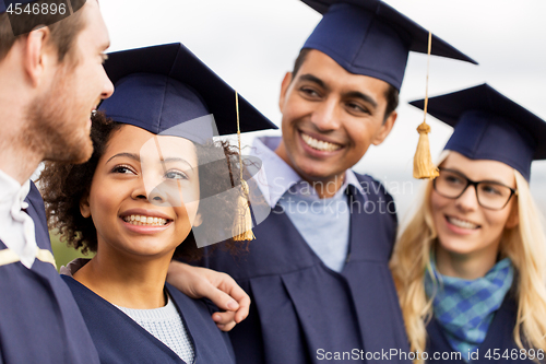 Image of happy students or bachelors in mortar boards