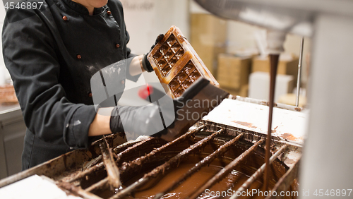 Image of confectioner cleaning chocolate mold by spatula