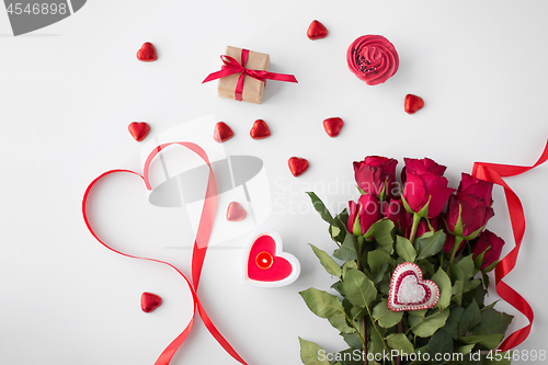 Image of close up of red roses, gift, candies and candle