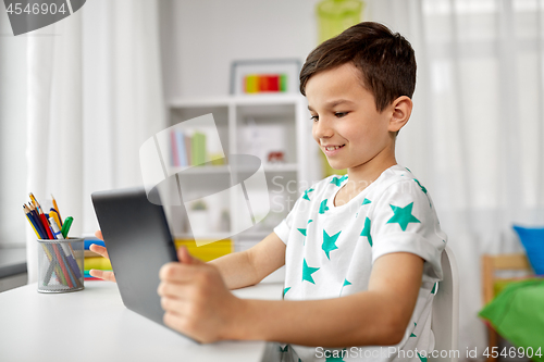 Image of student boy with tablet pc and notebook at home