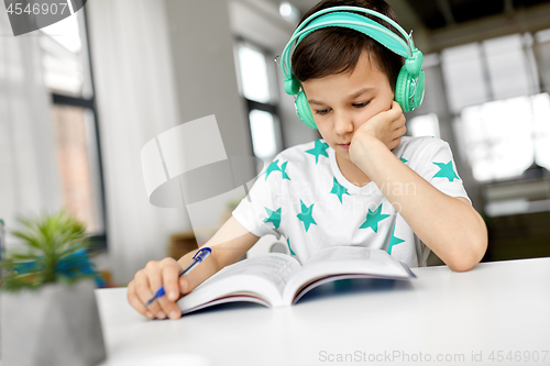 Image of boy in headphones with textbook learning at home