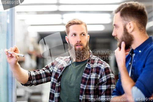 Image of men writing to clipboard and whiteboard at office