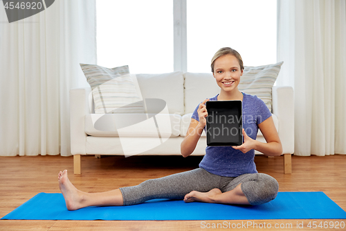 Image of woman with tablet computer doing yoga at home