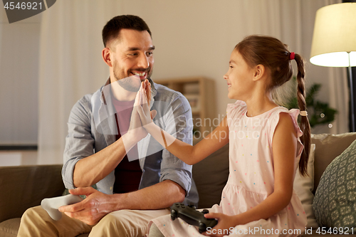 Image of father and daughter playing video game at home