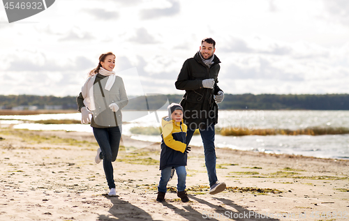 Image of happy family running along autumn beach