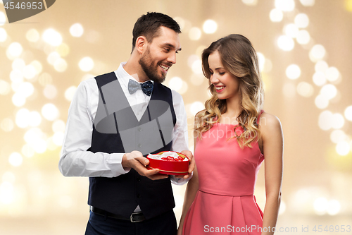 Image of happy couple with chocolate box in shape of heart