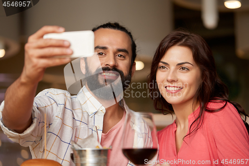 Image of couple taking selfie by smartphone at restaurant