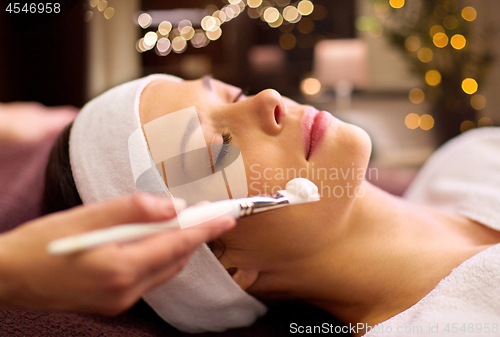 Image of beautician applying facial mask to woman at spa