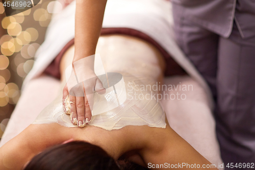 Image of woman having back massage with cream at spa