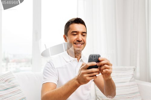 Image of happy man with smartphone at home