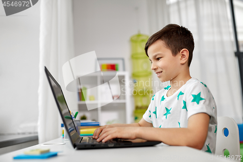 Image of student boy typing on laptop computer at home