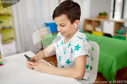 Image of boy in earphones listening to music on smartphone