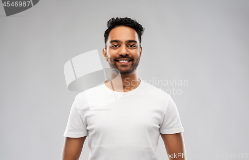 Image of smiling young indian man over gray background