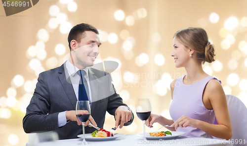 Image of smiling couple eating main course at restaurant