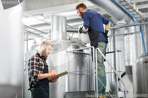 Image of men with clipboard at brewery kettle or beer plant