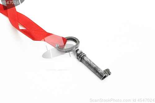 Image of Vintage silver key on red ribbon on white background