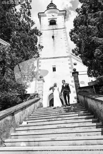 Image of The Kiss. Bride and groom kisses tenderly on a staircase in front of a small local church.