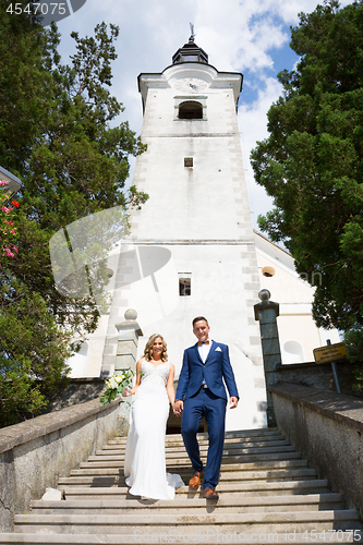 Image of The Kiss. Bride and groom kisses tenderly on a staircase in front of a small local church.