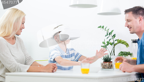 Image of Happy caucasian family at home at dinning table, having fun playing games using virtual reality headset