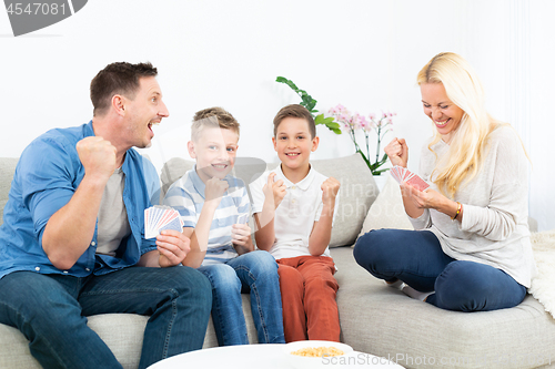 Image of Happy family playing card game on living room sofa at home and having fun together celebrating the game winner