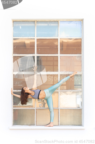 Image of Fit sporty active girl in fashion sportswear doing yoga fitness exercise in front of gray wall, outdoor sports, urban style