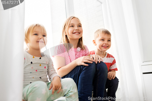 Image of happy little kids sitting on window sill