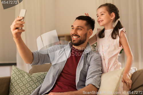 Image of father and daughter taking selfie at home